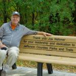 Parks Director Joe Nehmer sitting on recognition bench with incription