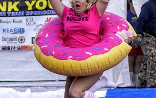 Lady in Pink donut costume jumping into frozen Lake Ripley at Dip for Dozer