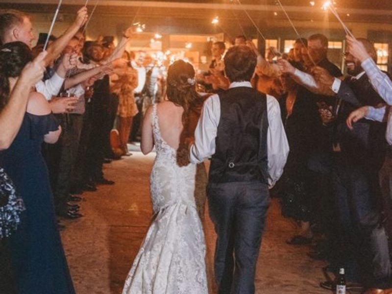 Wedding couple walking through tunnel of people with sparklers