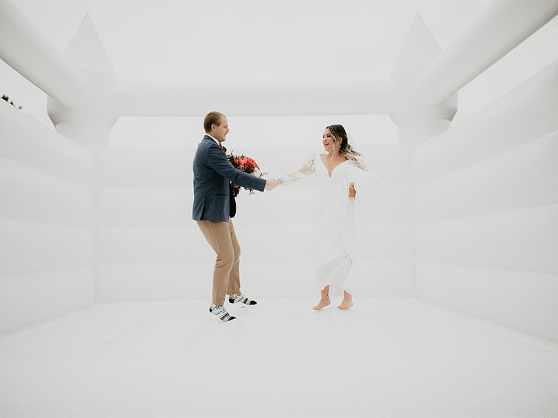 couple jumping in white elegant bounce house by Roar LG A Fun-Filled Wedding at Bennett Barn in Watertown